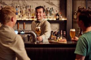 Ein Mann steht in einer Bar mit einem Barkeeper. in der Unterkunft Van der Valk Hotel Breukelen in Breukelen