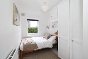 a small white bedroom with a bed and a window at Magnificent Maida Vale 1bd apt for 3 in London