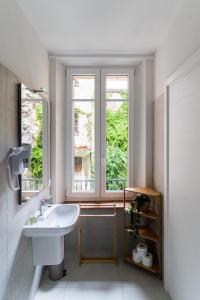 a white bathroom with a sink and two windows at Residenza Leoncino in Verona