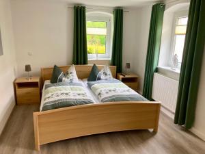 Schlafzimmer mit einem großen Bett und grünen Vorhängen in der Unterkunft Ferienwohnung "Am Kirchsteig" in Kurort Gohrisch