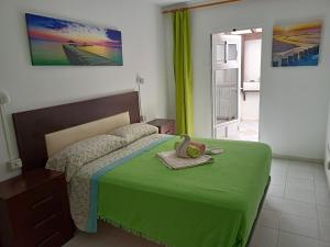 1 dormitorio con 1 cama con edredón verde en Ocean and Relax Apartment, en Corralejo