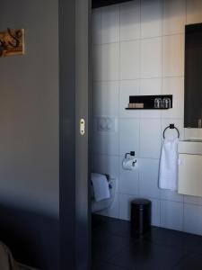 a bathroom with a toilet and a white tiled wall at Rey Apartments in Reykjavík