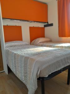 2 łóżka w pokoju z pomarańczowymi ścianami w obiekcie Agricampeggio Le Corniole w mieście Affi