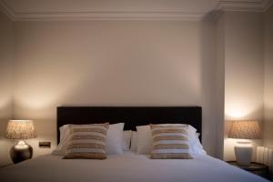 ein Schlafzimmer mit einem Bett mit Kissen und zwei Lampen in der Unterkunft Apartamento Exterior 2 dormitorios en CENTRO HISTÓRICO in San Lorenzo de El Escorial