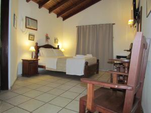 1 dormitorio con 1 cama y 1 silla en La Posada de Akasha en Villa General Belgrano