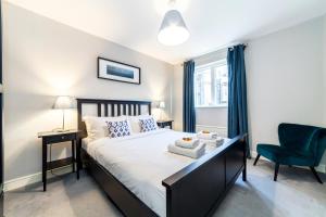 a bedroom with a bed and a blue chair at Lovely 2 BR Notting Hill flat wgarden in London