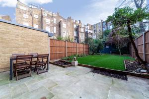 a patio with a table and chairs and a yard at Lovely 2 BR Notting Hill flat wgarden in London