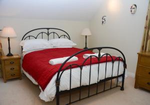a bedroom with a bed with a red blanket and white pillows at Coach House Cottage in Middleton