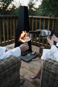 a person pouring a glass of wine in front of a fireplace at Yurtshire Eavestone Lake - Birch Yurt in Ripon