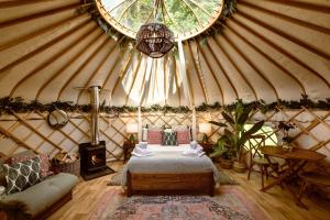 um quarto numa tenda com uma cama e um sofá em Yurtshire Eavestone Lake - Birch Yurt em Ripon