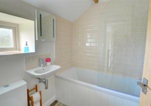 a bathroom with a bath tub and a sink at Coach Cottage in Gilling East