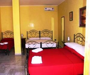 a bedroom with two beds with red sheets at B&B Santa Lucia in Sogliano Cavour
