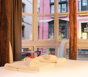 a table with two towels on a table in front of a window at Pensión AliciaZzz Bed And Breakfast Bilbao in Bilbao