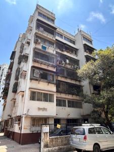 un edificio alto con un coche aparcado delante de él en Hotel Plaza Rooms - Prabhadevi Dadar en Bombay