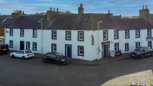 a group of white houses with cars parked in a parking lot at The Harbour Inn in Garlieston