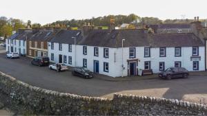 eine Gruppe weißer Häuser mit Autos, die in einer Straße geparkt sind in der Unterkunft The Harbour Inn in Garlieston