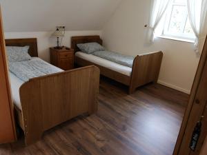 2 łóżka w pokoju z drewnianą podłogą i oknem w obiekcie Gästezimmer Emmis Erbe w mieście Peine