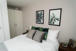 ein Schlafzimmer mit einem weißen Bett mit vier Kissen in der Unterkunft Chic Apartments and Studios at The Point in Aberdeen in Aberdeen