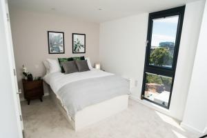 una camera bianca con un letto e una grande finestra di Chic Apartments and Studios at The Point in Aberdeen ad Aberdeen