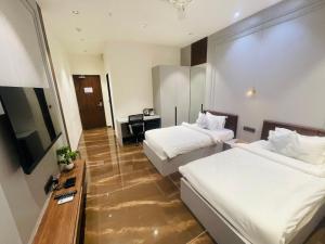 Habitación de hotel con 2 camas y TV en VITS Jamnagar, en Jamnagar