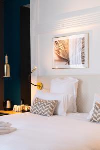 Un dormitorio con una cama blanca con una foto en la pared en Hôtel D'Anjou en Angers