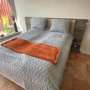 ein Bett mit einer orangefarbenen Decke darüber in der Unterkunft Ferienwohnung 1 Zimmer App Ankerplatz 43 im Olympiazentrum in Kiel