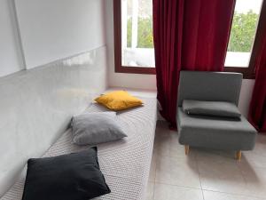 Habitación con 2 almohadas, silla y ventana en Birds Villa Apartments - Including Car Rental, en Perissa