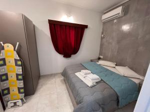 a small bedroom with a bed with a red curtain at Birds Villa Apartments - Including Car Rental in Perissa