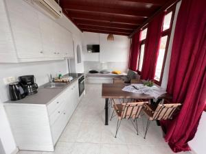 una cocina con armarios blancos y una mesa con sillas. en Birds Villa Apartments - Including Car Rental en Perissa