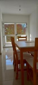 a dining room with a table and chairs and two windows at Pampa Modern Apartment in Simoca