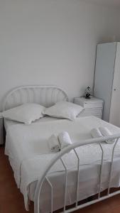 een wit bed met witte lakens en kussens bij Apartment BIM in Pisak