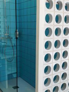y baño con ducha de azulejos azules. en Hotel La Potiniere en Hyères