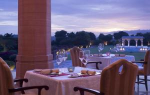 two tables with wine glasses sitting on a patio at Umaid Bhawan Palace Jodhpur in Jodhpur