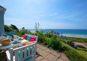 a table and chairs on a patio with a view of the ocean at Pooh Corner in Praa Sands