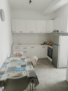 een keuken met een tafel met stoelen en een koelkast bij Apartment BIM in Pisak