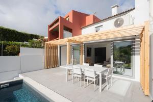 a patio with a table and chairs next to a swimming pool at Figueiras House Pópulo Beach in Ponta Delgada
