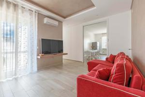 a living room with a red couch and a television at Appartamento Vitalba by BarbarHouse in Ginosa Marina
