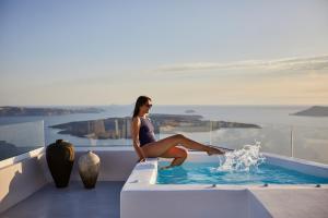 a woman sitting on the edge of a swimming pool at Damigos Caldera World in Firostefani