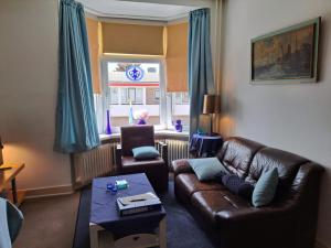 a living room with a leather couch and a table at Sharon's Studio Blue in Maastricht