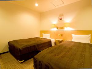 Habitación de hotel con 2 camas y 2 lámparas en Okano Hotel, en Sendai