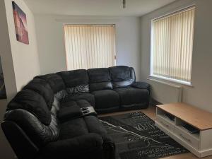 un sofá de cuero negro en una sala de estar con mesa en Comfy One bedroom Apartment en Londres