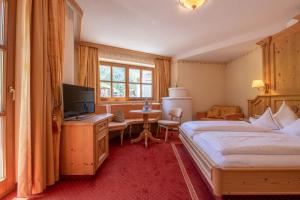 a bedroom with a bed and a television and a desk at Natur-&Alpinhotel Post in Vent