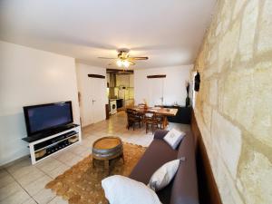 a living room with a couch and a tv at Maison de vacances Gite le Margot in Cantenac