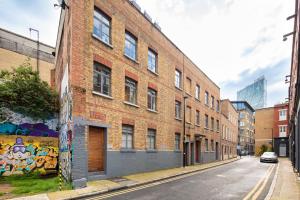 a brick building with graffiti on the side of it at Spitalfields one bedroom apartment in London