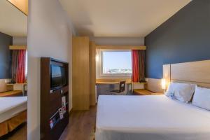 um quarto de hotel com uma cama e uma televisão em ibis Barretos em Barretos