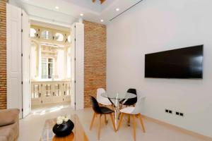 a living room with a table and chairs and a tv at INMálaga Santos Suites 1 in Málaga