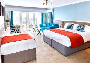 a hotel room with two beds and a chair at Trearddur Bay Hotel in Trearddur
