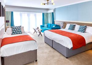 a hotel room with two beds and a chair at Trearddur Bay Hotel in Trearddur
