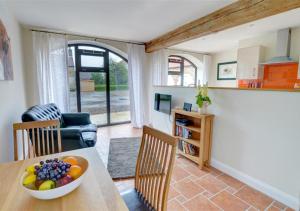 a kitchen and living room with a table with a bowl of fruit at Clematis Cottage in Gilling East