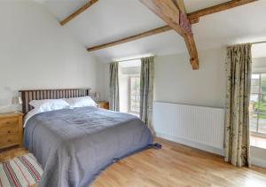a bedroom with a bed and two windows at Clematis Cottage in Gilling East